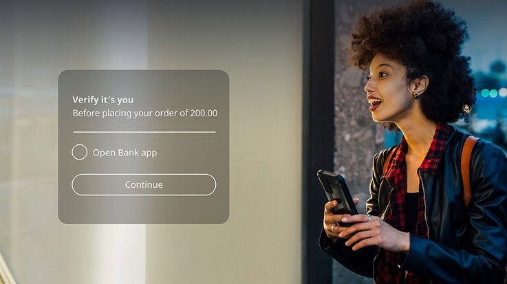 A woman with a smartphone in her hand looks enthusiastically through a shop window