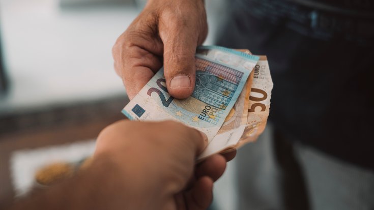 Close up of two persons handing over euro money bills