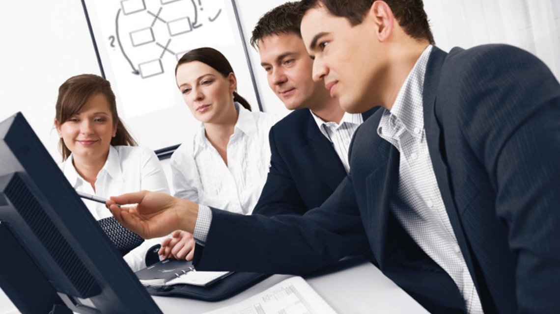 A businessman explains something to his colleagues on a computer screen