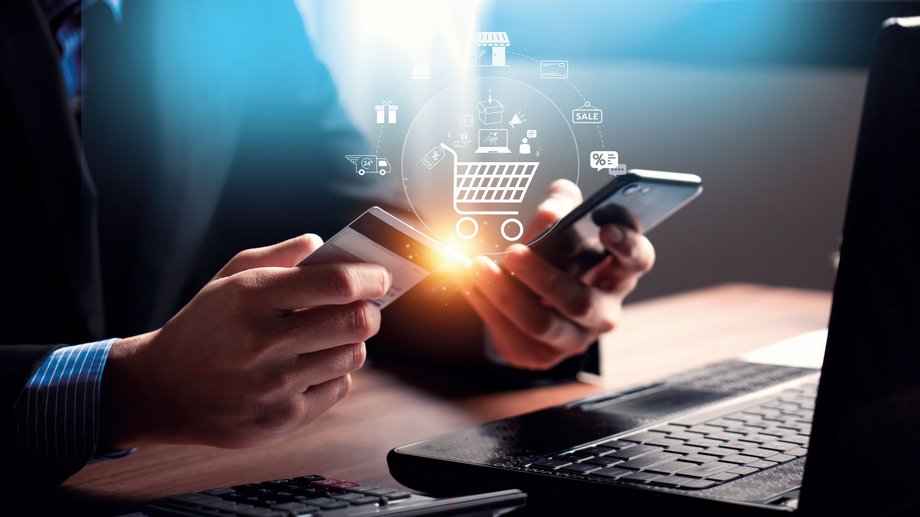 a person holding a smartphone a bank card in front of a laptop with visuals