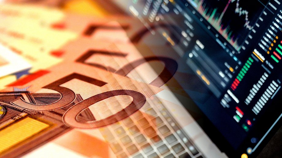 fifty euro bills in front of a computer screen with charts