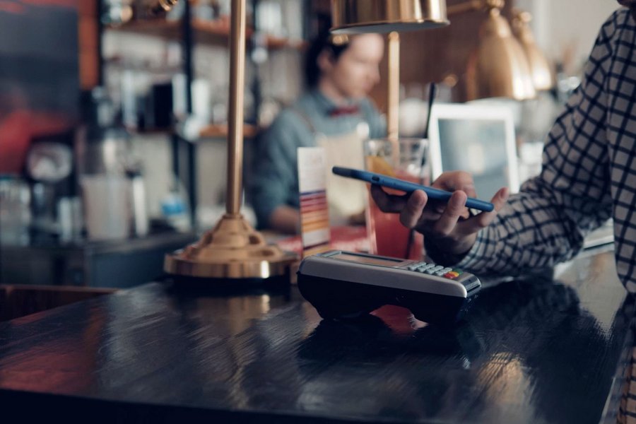 A man pays contactless with his smartphone at a bar