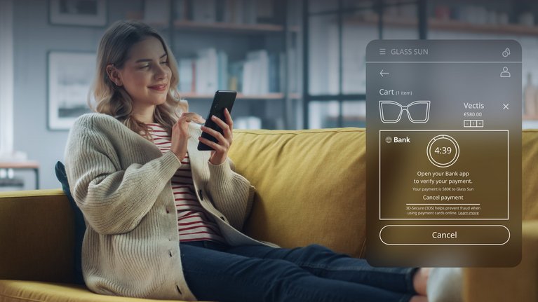 A woman holds her smartphone and confirms an online purchase at her bank