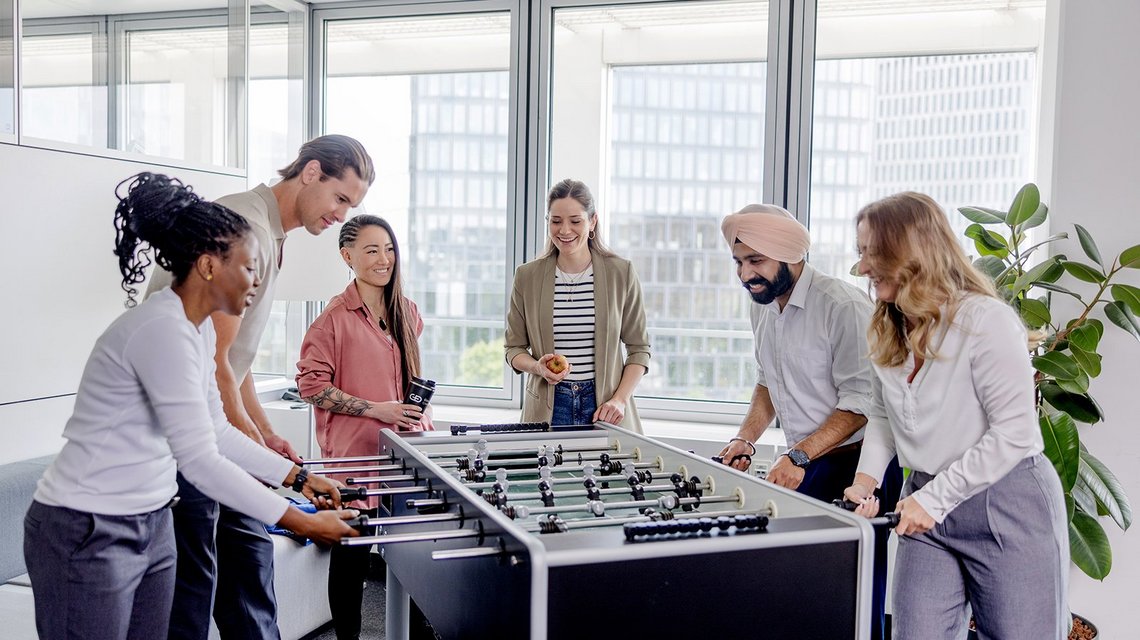 Colleagues playing table football in the office