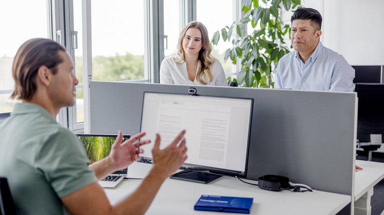 Colleagues discussing at a computer in the office