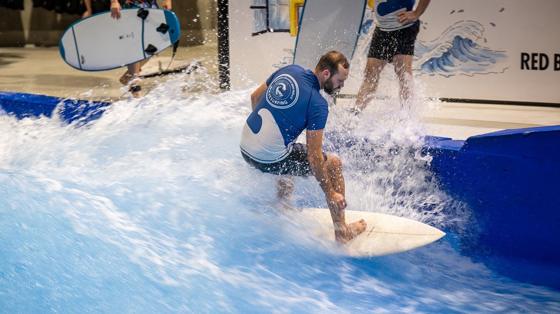Person surfing on artificial wave indoors