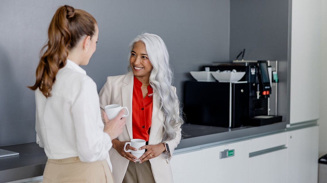 Two colleagues chatting over coffee in the office