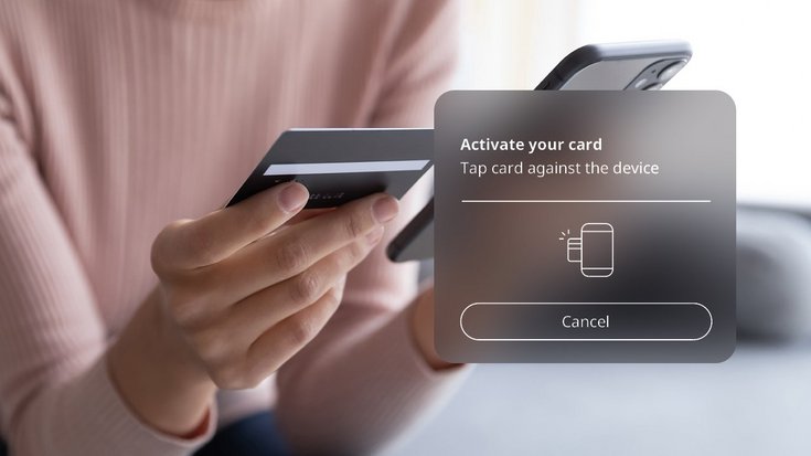 Person is holding their smartphone and payment card in their hand and is in the process of activating the payment card