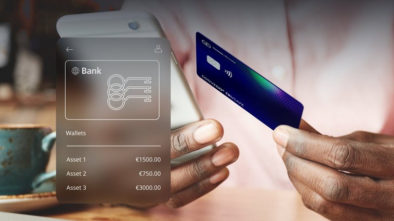 A person holding a smartphone displaying a bank application interface and a payment card