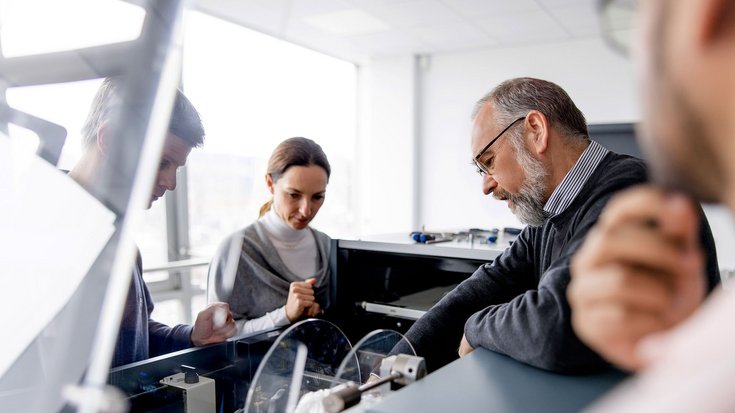 Four men are participating in a training session, working together on a G+D product in an office setting
