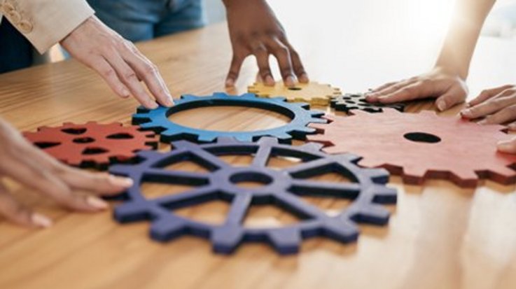 Several hands join colorful gear pieces on a table.
