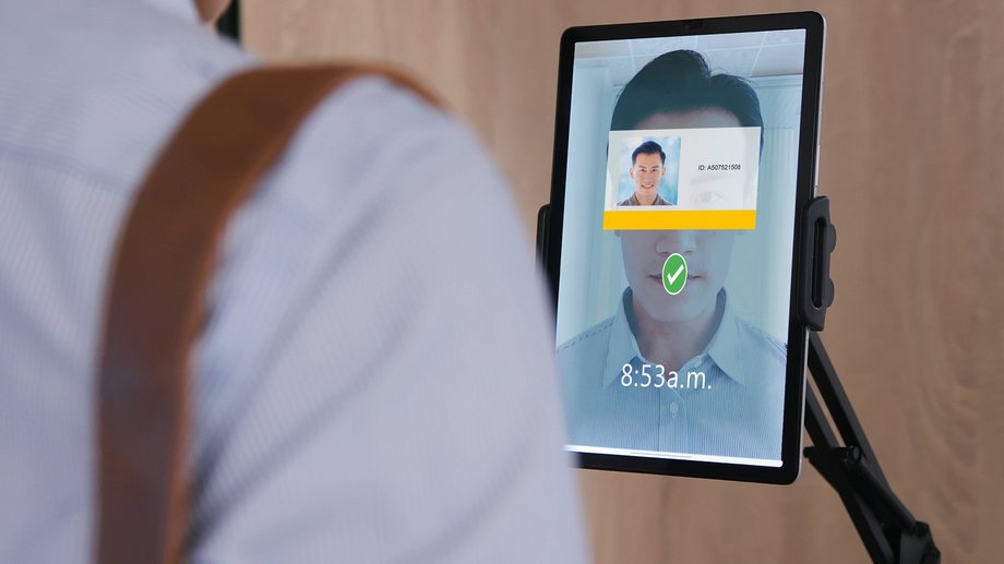Person scans their face on a tablet for facial recognition to authenticate themselves.