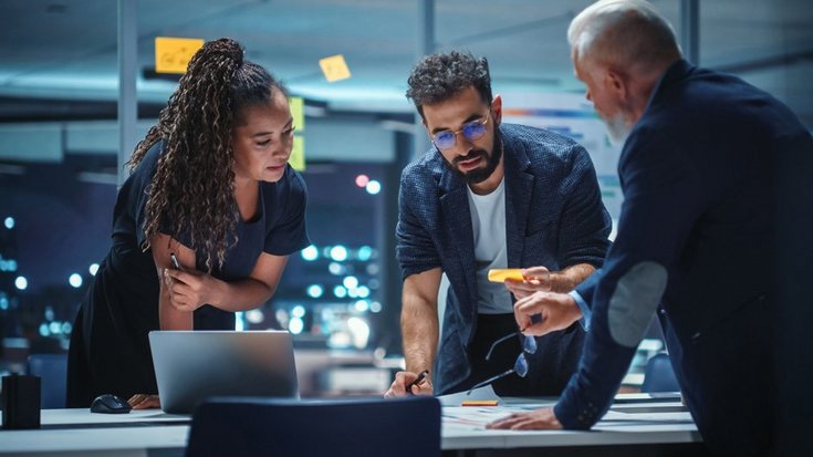 Three business people discussing work late in the office
