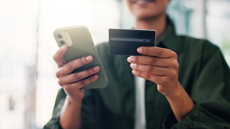 Person holding a smartphone and a credit card