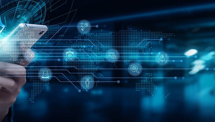 Person using a tablet in a modern control room with multiple computer screens.