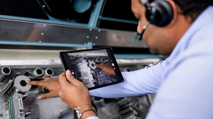 An engineer using a tablet to analyze machinery components.