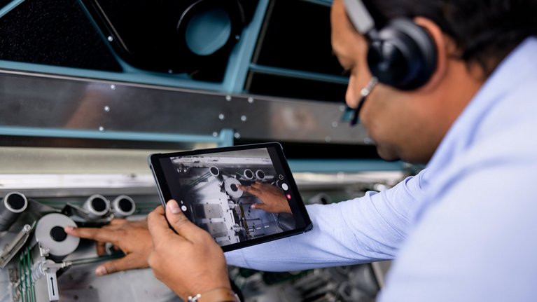 An engineer using a tablet to analyze machinery components.