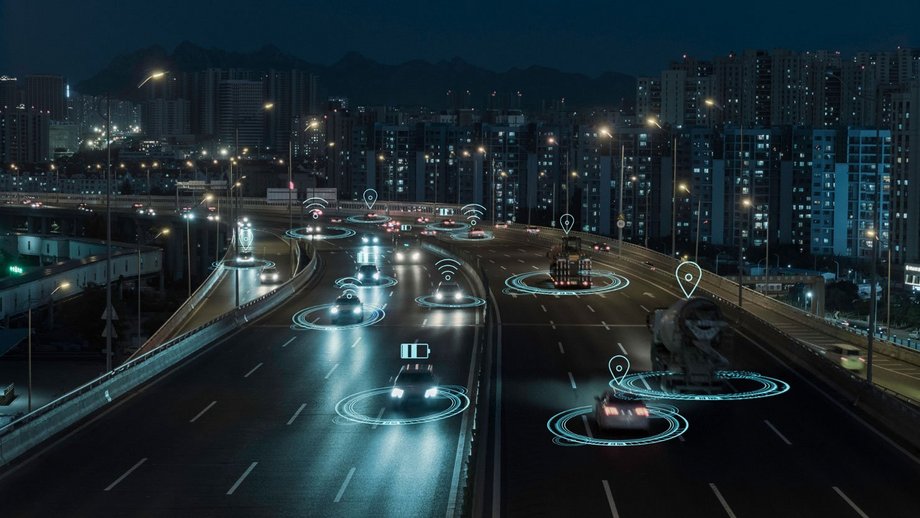 Autonomous vehicles on illuminated city road at night.