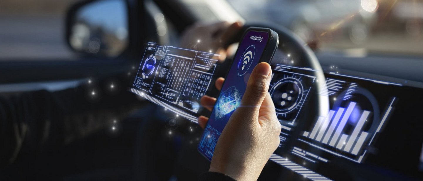 Hand holding smartphone in car with digital displays.