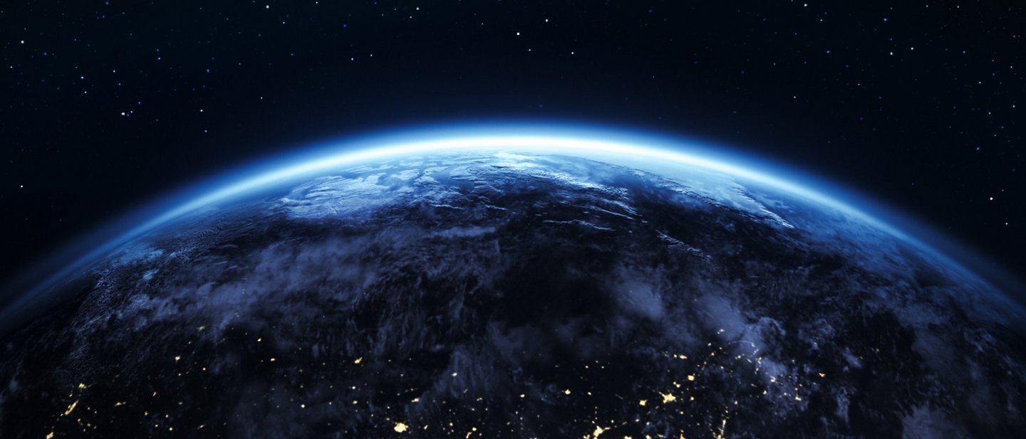 View of planet Earth from space with glowing atmosphere, illuminated lights, and a starry night sky