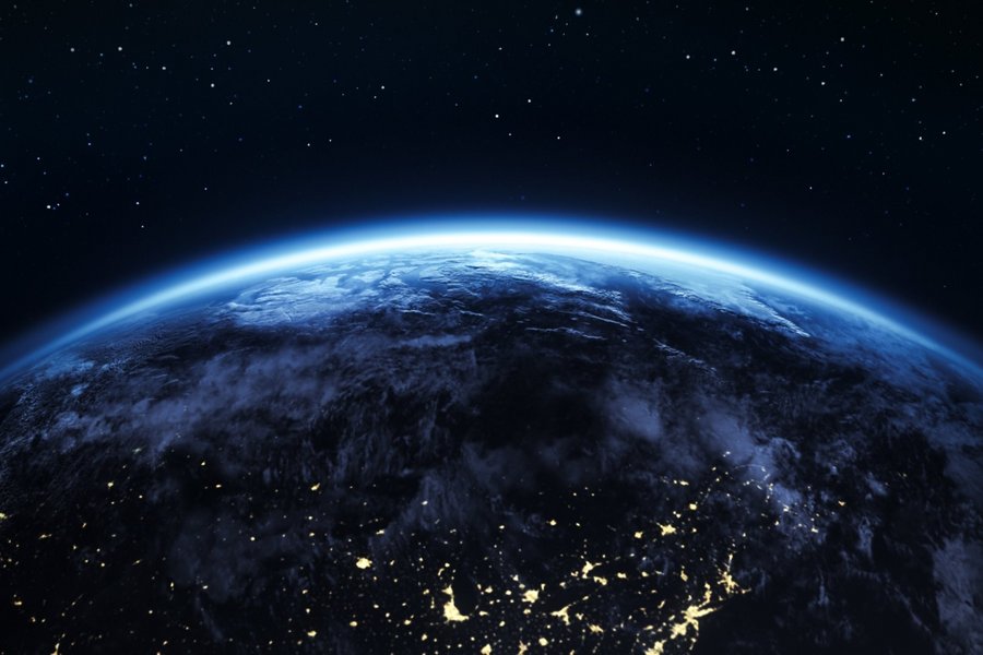 View of planet Earth from space with glowing atmosphere, illuminated lights, and a starry night sky
