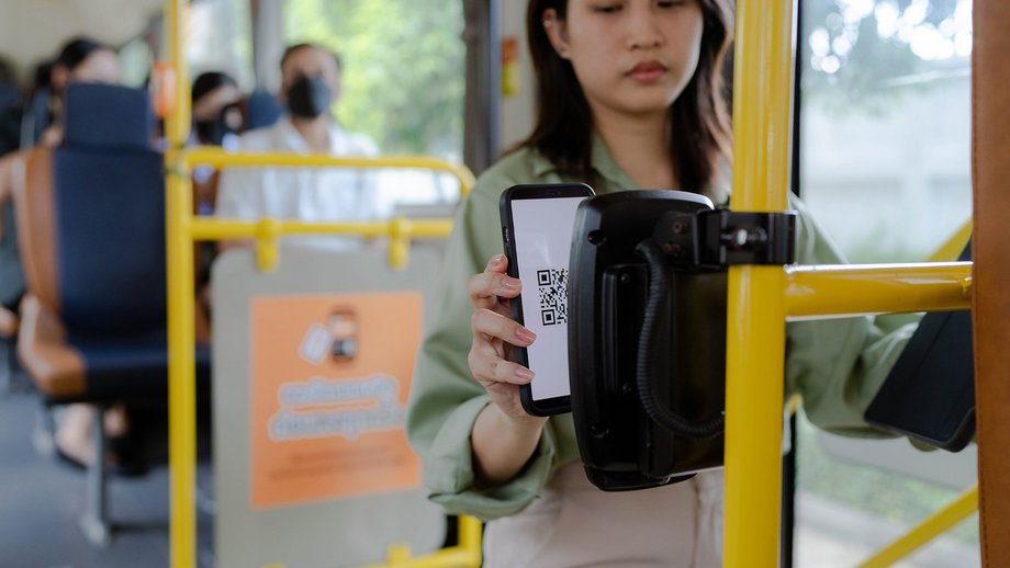 A person scanning a QR code on their smartphone in a bus