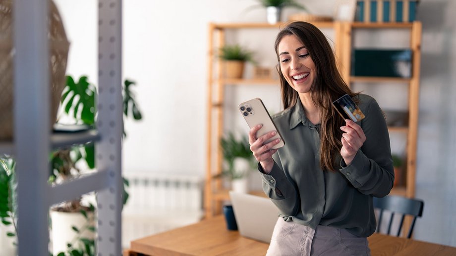Woman compares financial expenses using a credit card and mobile wallet.