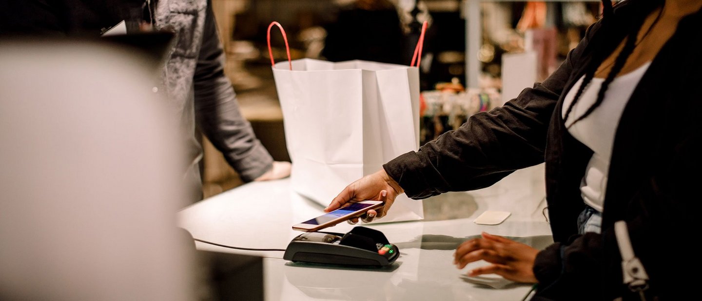 Woman uses her smartphone to make a digital payment for her shopping, showcasing mobile payments