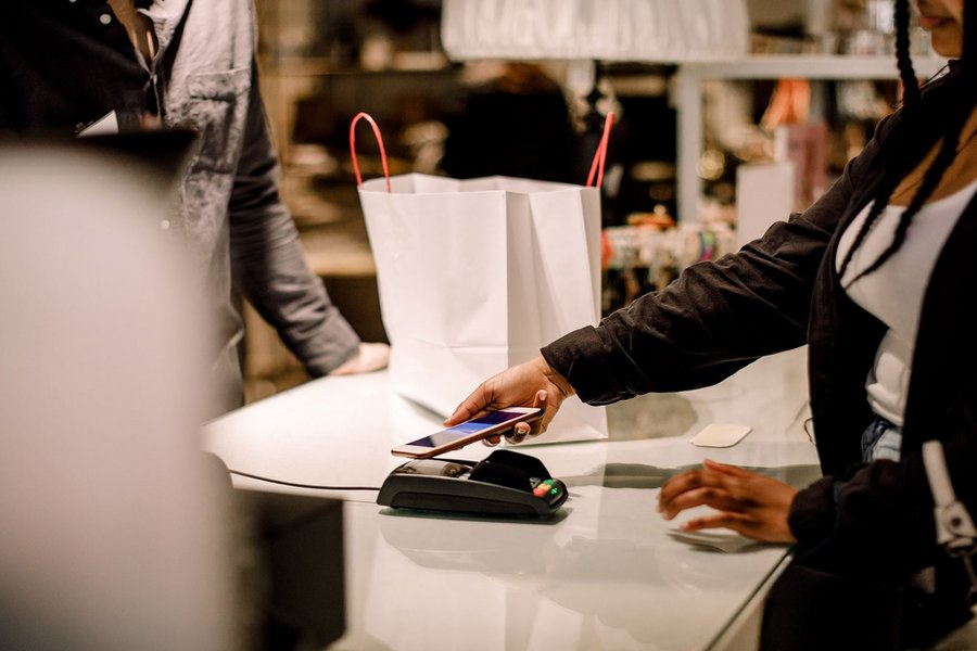Woman uses her smartphone to make a digital payment for her shopping, showcasing mobile payments