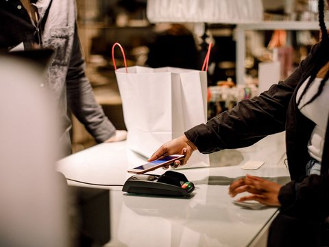 Woman uses her smartphone to make a digital payment for her shopping, showcasing mobile payments