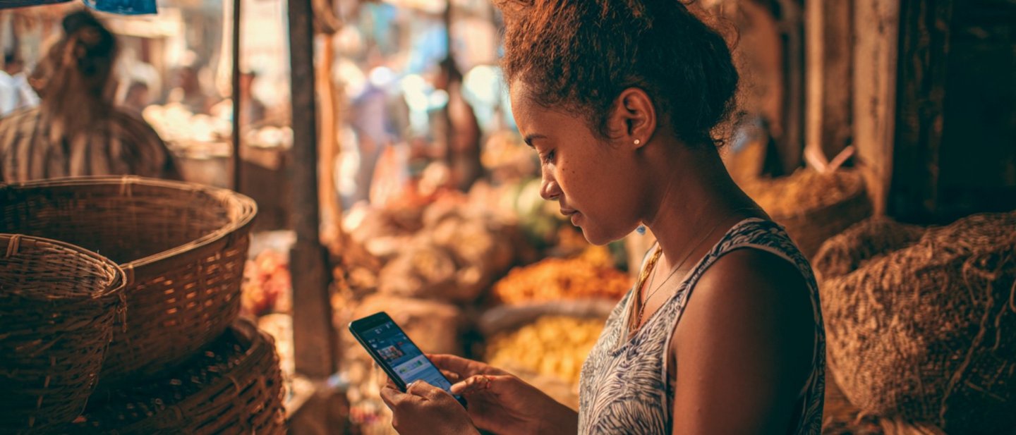 A Brazilian woman uses a CBDC app for making a payment on her smartphone while being at a market.