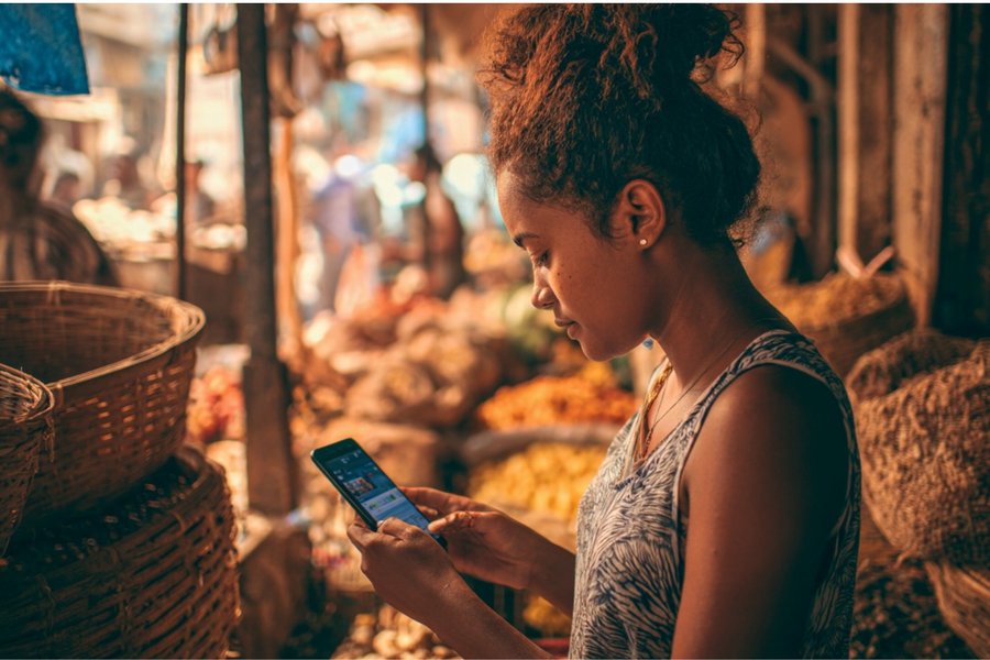 A Brazilian woman uses a CBDC app for making a payment on her smartphone while being at a market.