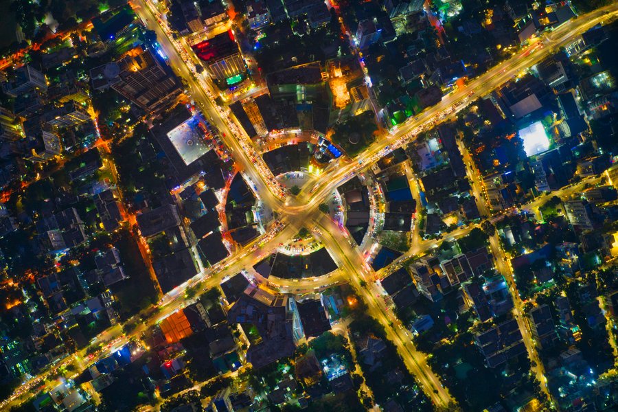 Aerial view of a city intersection at night, showing a traffic circle with radiating roads