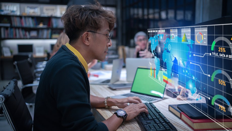 A developer works with data visualization and graphics on a futuristic monitor using AI technology.