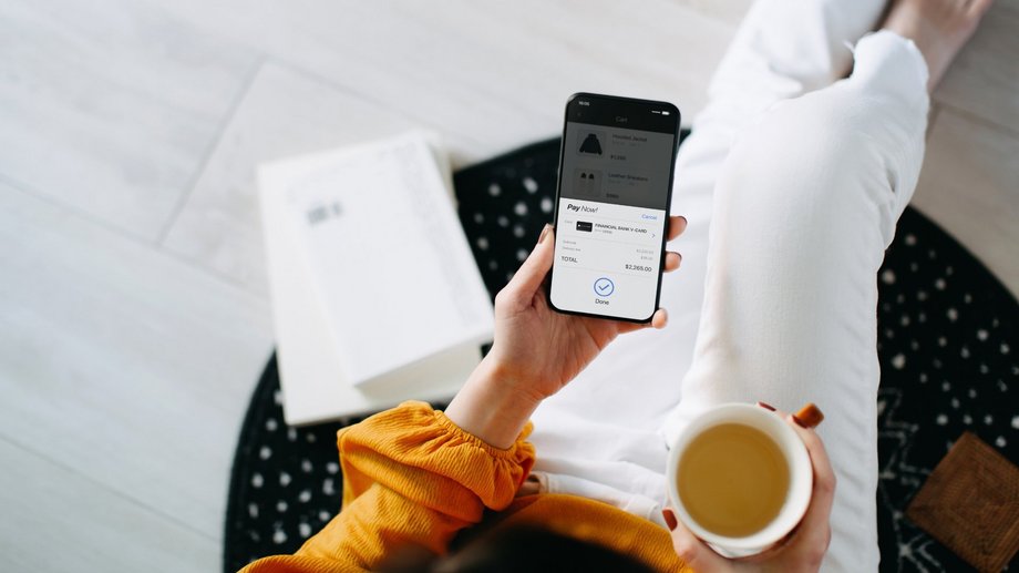 Person holding a smartphone with a banking app while enjoying a cup of coffee.