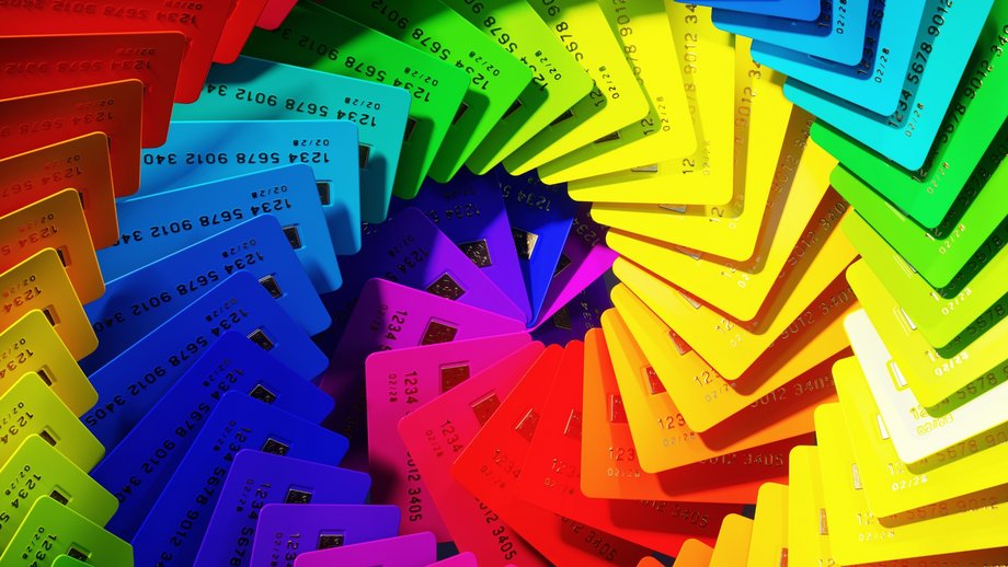 Numerous bright, colorful credit cards in rainbow colors arranged in a spiral pattern.
