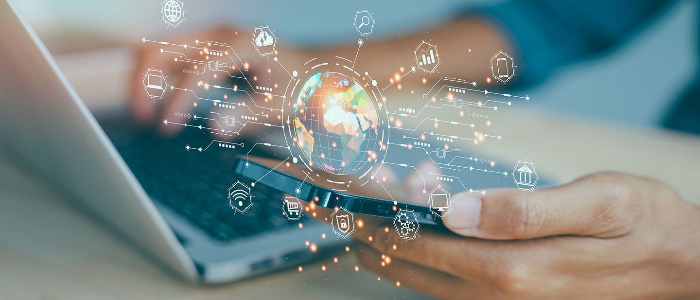 Person using a laptop and smartphone with a digital globe and network icons in the foreground.