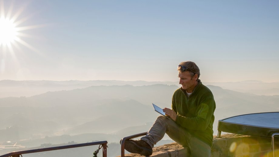 Park ranger using a tablet outdoors with a view of misty mountains at sunrise