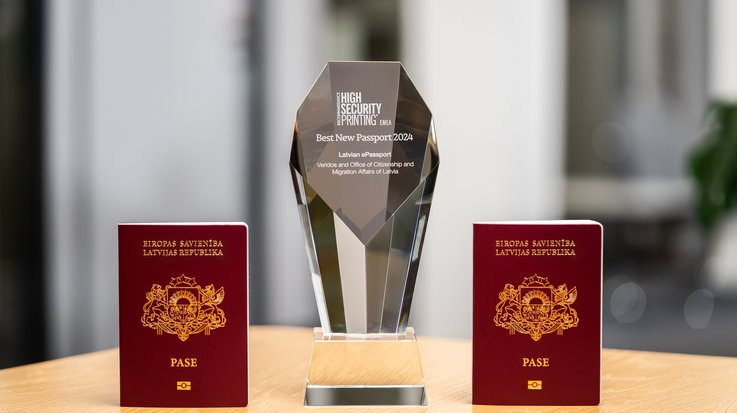 Two frontally photographed Latvian passports with Veridos Award in between