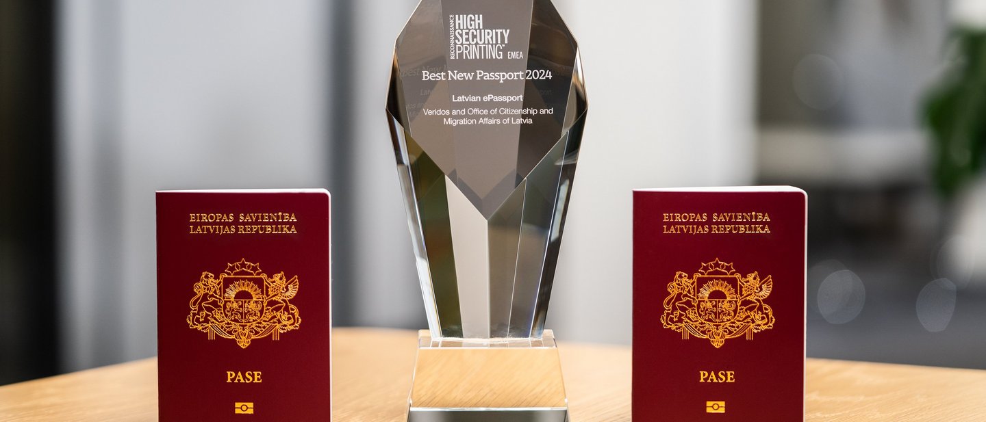 Two frontally photographed Latvian passports with Veridos Award in between
