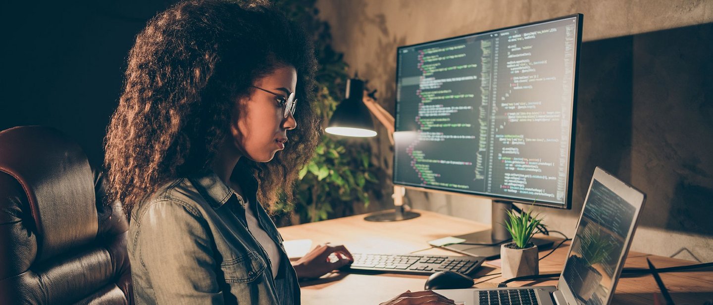 A woman sits at a desk and works concentratedly on her laptop.