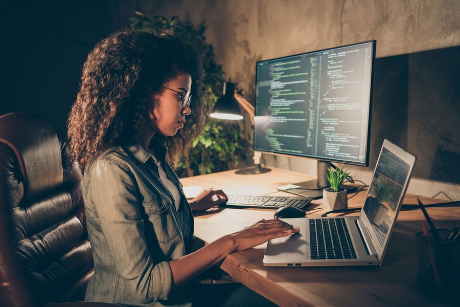 A woman sits at a desk and works concentratedly on her laptop.