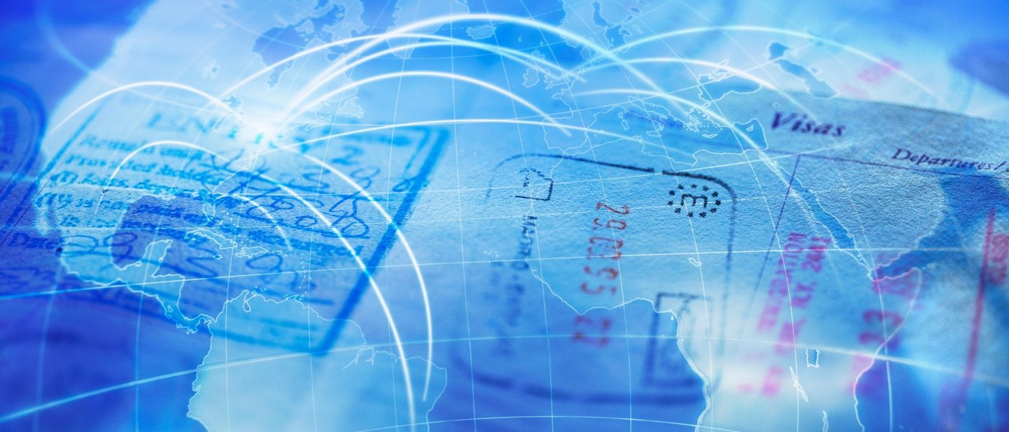 A passport full of different stamps lies on a blue colored world map with travel destinations.