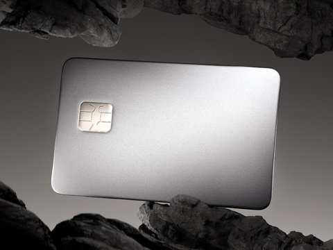 Luxurious, metallic credit card with a chip, dramatically lit, between dark, rocky formations