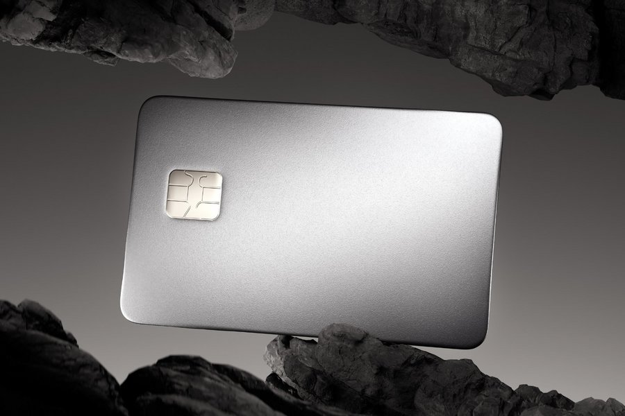 Luxurious, metallic credit card with a chip, dramatically lit, between dark, rocky formations