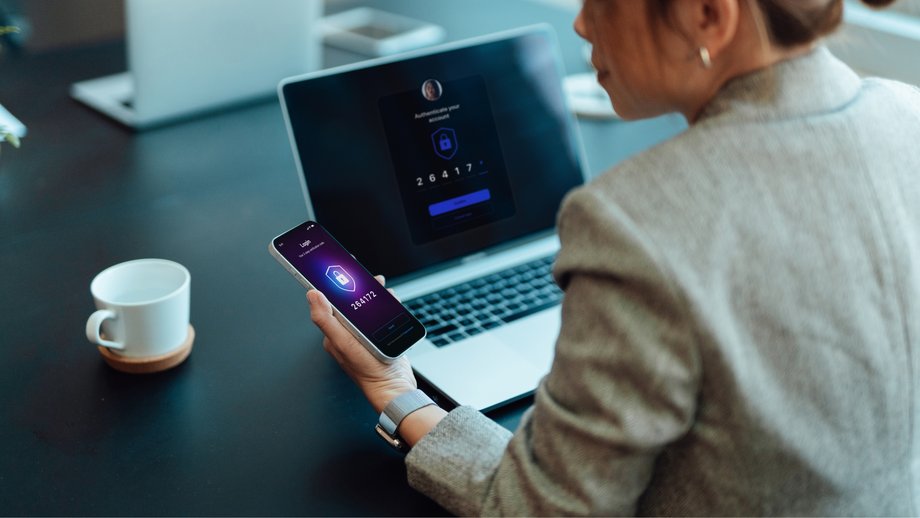 Person using smartphone for authentication on laptop