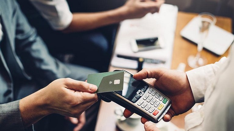 In man in business attire pays contactless with his credit card in a restaurant