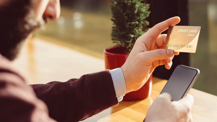 A man holds his credit card in one hand and his smartphone in the other