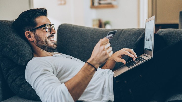 Man at home buying online on his laptop with a card 