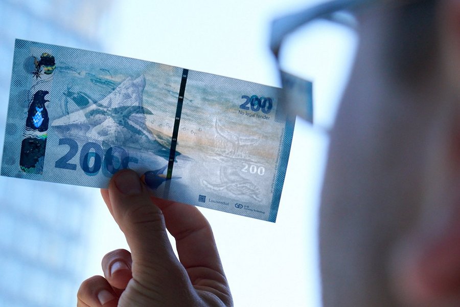 An employee of Giesecke + Devrient is checking a banknote